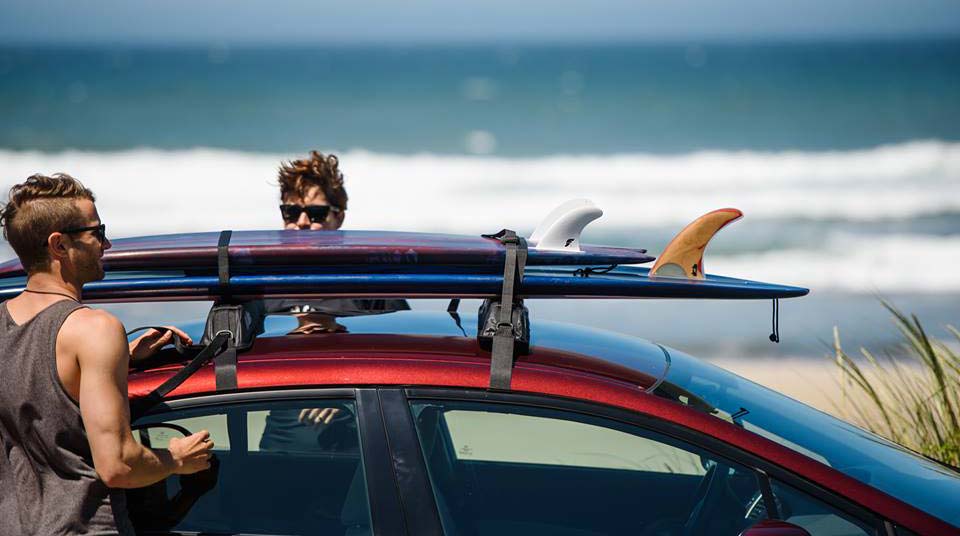 Coche transportando una tabla de surf con una baca de quitar y poner