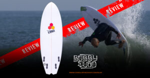Una tabla de surf Al Merrick Bobby Quad blanca con logotipos hexagonales se encuentra en posición vertical. Bobby Quad realiza una maniobra aérea en el océano. El texto dice "REVIEW", "BOBBY QUAD" y "BLOG.CORESURFINGSHOP.COM".