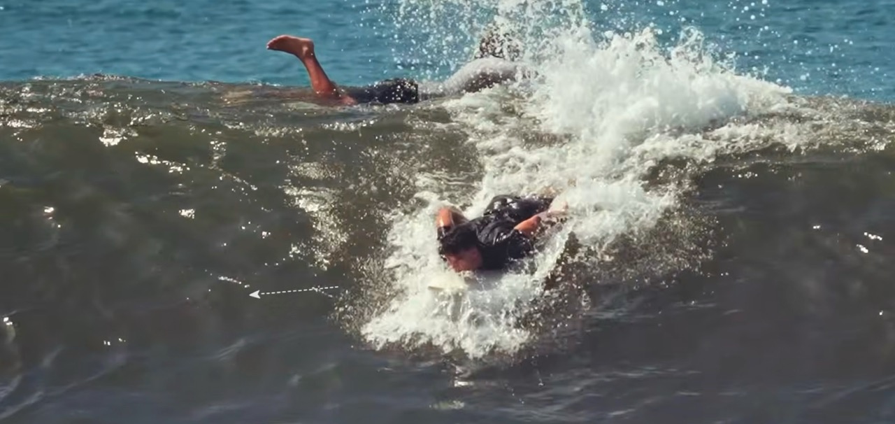 Surfista remando una ola con la tabla a 45 grados hacia la pared para ganar velocidad